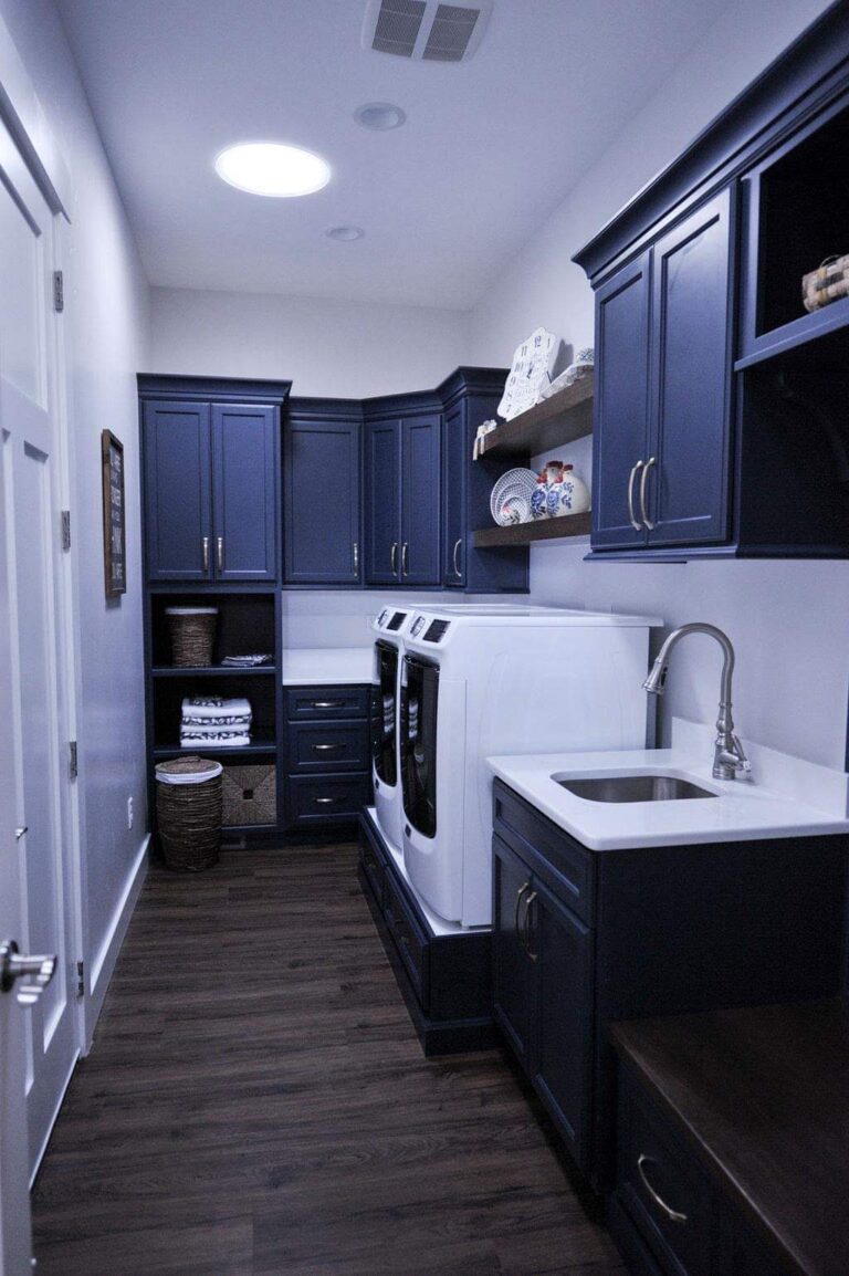 Utah laundry room remodel with custom navy cabinets, built-in washer and dryer, and utility sink.